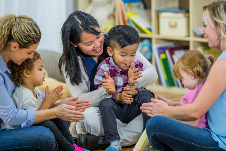 Children singing and clapping with caregivers at the library