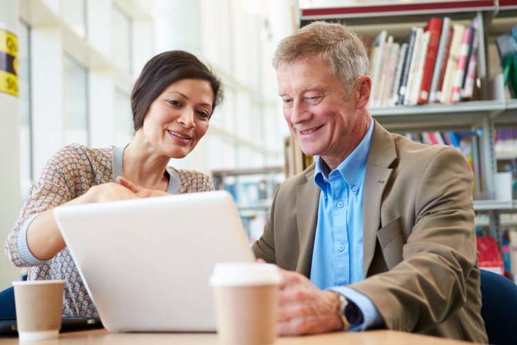 A woman and an older man look at a computer screen together