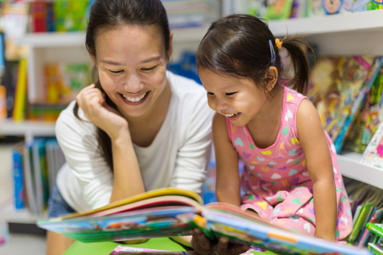 A mother and daughter read a picture book together at a library